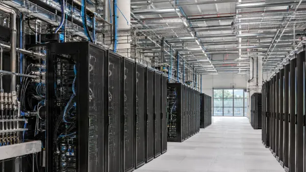 Filas de racks de servidores sin marca y refrigerados por líquido dentro de un moderno centro de computación de alto rendimiento