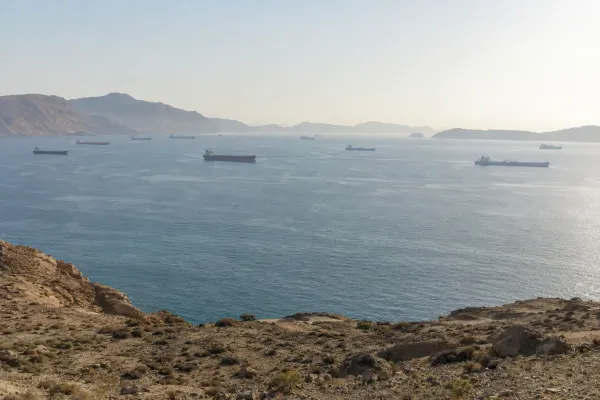 Commercial tankers crossing a hazy, mountainous strait under natural morning light