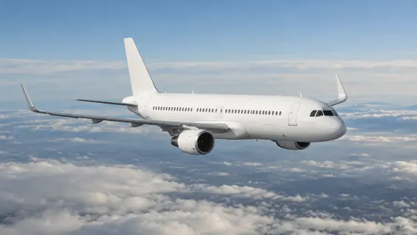 Unbranded passenger aircraft cruising above layered clouds in neutral daylight