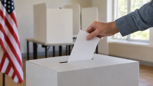 A voter places a blank ballot into a neutral ballot box in a quiet polling room.