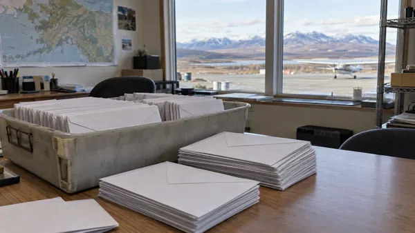Sealed blank ballot envelopes in a rural Alaska election office overlooking a small airstrip
