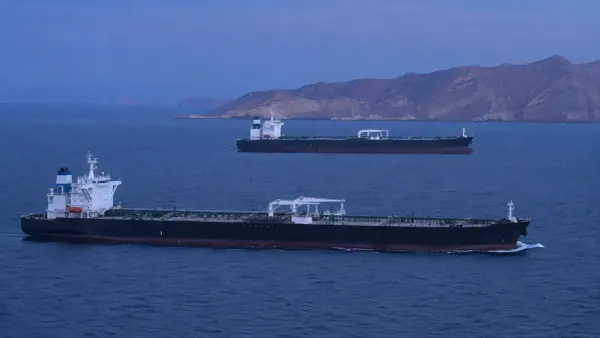 Dos buques cisterna sin distintivos que transportan petróleo crudo cruzan aguas azules y tranquilas cerca de la costa rocosa de Omán durante la hora azul