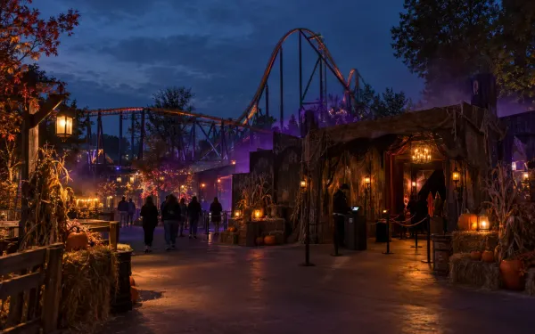 Illustrative fall nighttime amusement-park midway with a generic haunted attraction entrance and roller coaster.