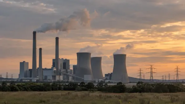 Coal- and gas-fired power station with cooling towers and transmission lines at dusk