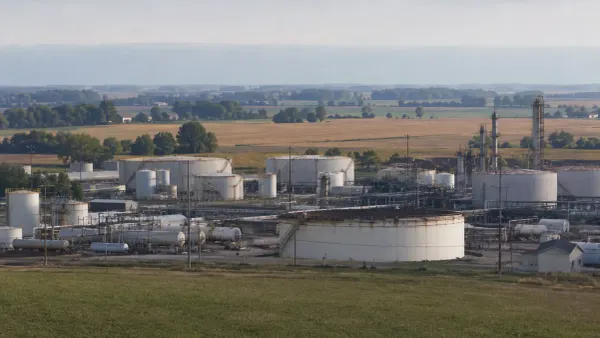 Refinadería regional de combustible sin marca y tanques de almacenamiento junto a tierras de cultivo del Medio Oeste, bajo la suave luz de la mañana