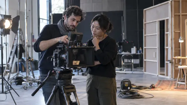 Two film professionals inspect an unbranded cinema camera inside an independent soundstage.