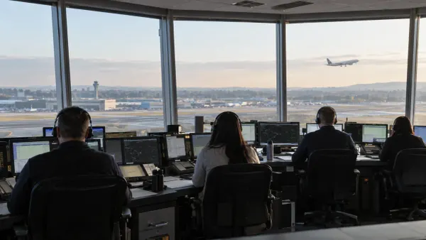 Air traffic controllers monitor communications consoles in a modern control facility as an aircraft approaches in daylight.