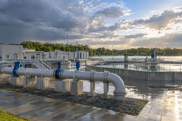 Water treatment plant and elevated pipes under clearing storm clouds