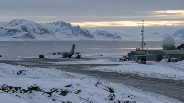 A generic Arctic military airfield beside a frozen fjord, with an unmarked transport aircraft, radar dome and communications tower.