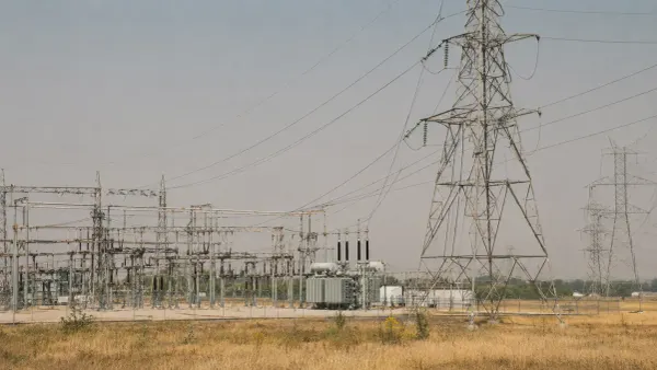 Electrical transmission towers and a large substation under hazy late-summer heat in the United States