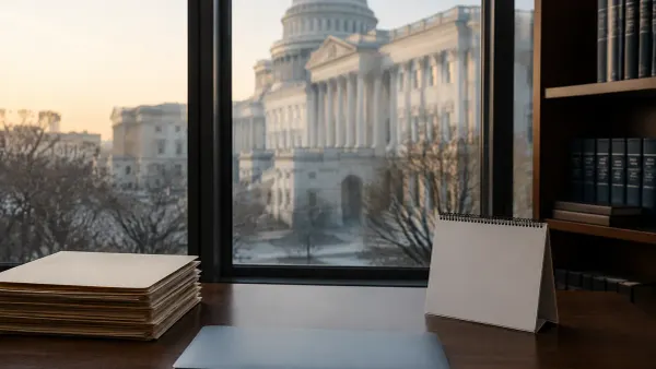 Blank folders, a closed laptop and an unmarked desk calendar in a quiet office overlooking the U.S. Capitol at dawn