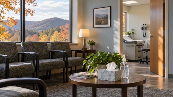 A quiet community health clinic waiting room with tissues and sanitizer as autumn foliage fills the windows.