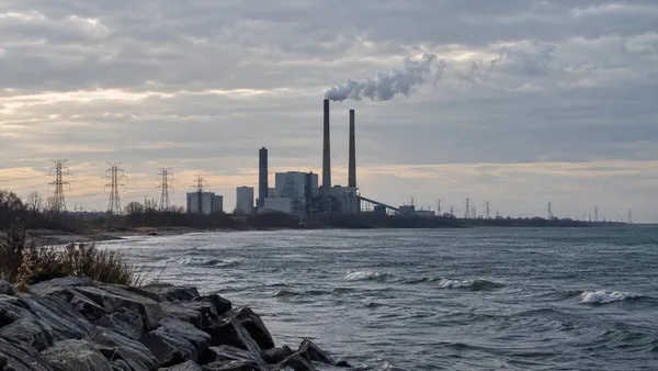 Conceptual view of a coal power station and transmission lines beside open water under an overcast sky