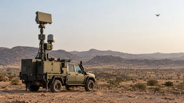 Unmarked mobile counter-drone radar vehicle tracking a small training drone over desert terrain