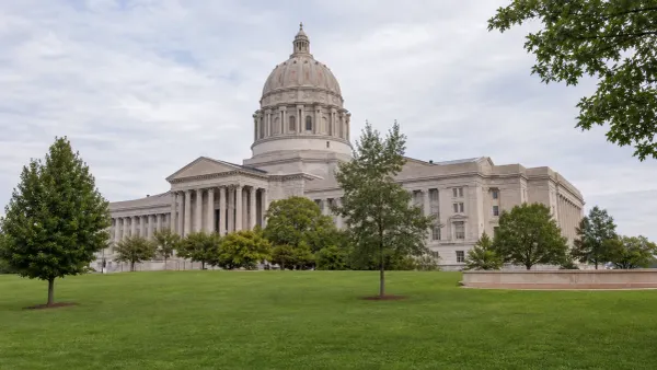A distant view of the Missouri State Capitol across a green lawn in soft morning daylight