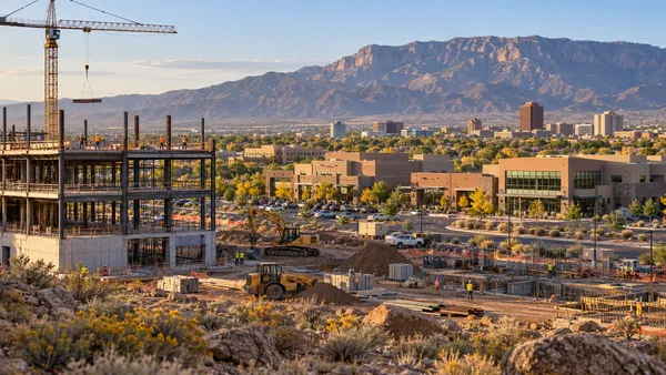 Construction activity amid commercial buildings in New Mexico’s high-desert landscape.