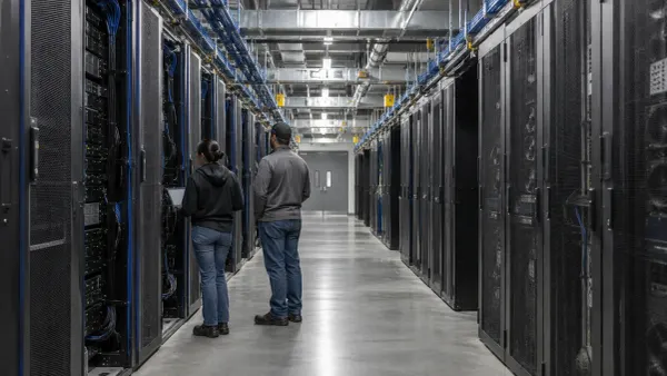 Técnicos inspeccionan racks de servidores dentro de un gran centro de datos de inteligencia artificial.