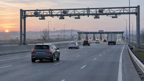 Vehicles traveling safely toward electronic tolling gantries and staffed toll booths on a wide highway at sunrise.