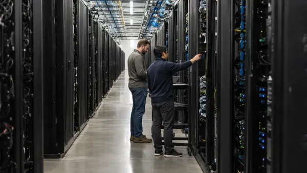 Técnicos inspeccionan filas de servidores sin marca en un gran centro de datos