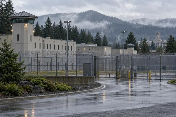 Illustrative view of a generic Oregon correctional facility behind perimeter fencing on a rainy morning