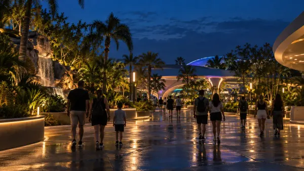 Visitors walk through a generic, palm-lined Florida theme park promenade during a low-crowd nighttime event.