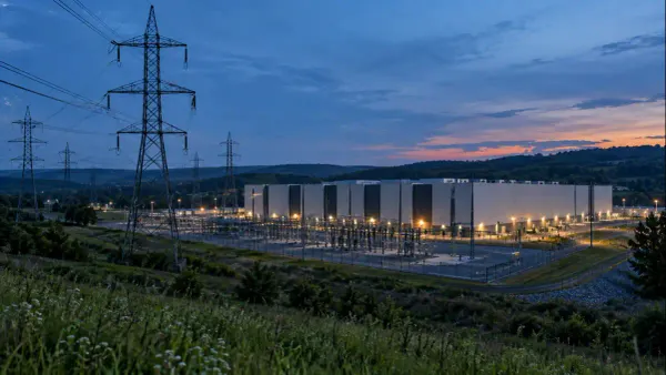 Transmission lines and an unbranded data center in a Pennsylvania-style landscape at dusk