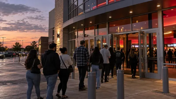 Moviegoers line up outside a contemporary multiplex at dusk.