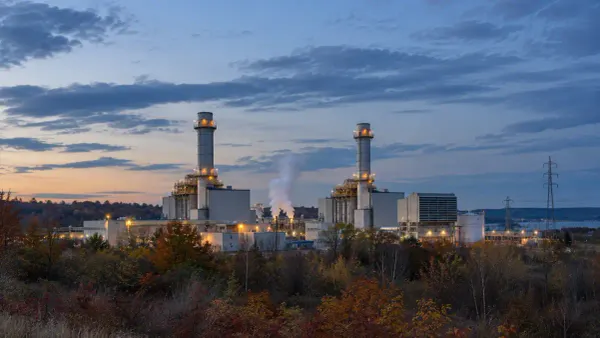Generic combined-cycle power station at blue hour with autumn trees and transmission lines