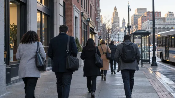 Workers walk toward offices and businesses along a Providence streetscape during the morning commute.