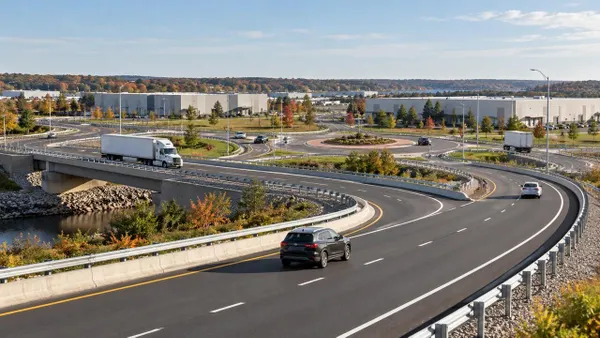 Illustrative aerial view of new highway ramps and a roundabout serving an industrial business park in early autumn