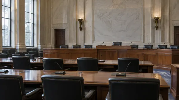 Empty congressional hearing room with wood desks and microphones in natural daylight