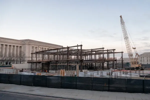 Structural steel, scaffolding and a construction crane at an unbranded federal building site in soft morning light