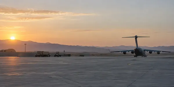 Um avião de transporte militar num pátio tranquilo de uma base aérea ao amanhecer, representando a retirada completa das tropas americanas do Iraque