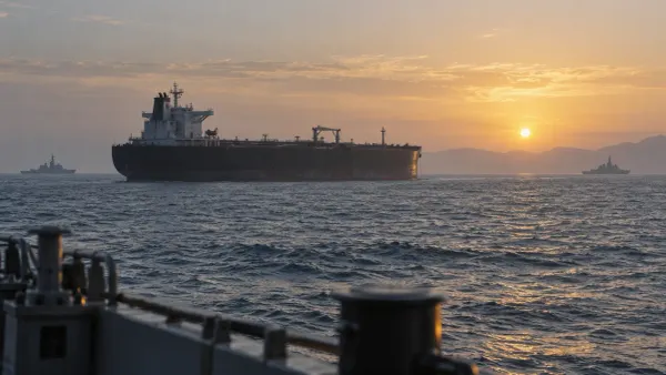 An unmarked oil tanker crosses calm Persian Gulf waters at dawn with distant naval vessels on the horizon.