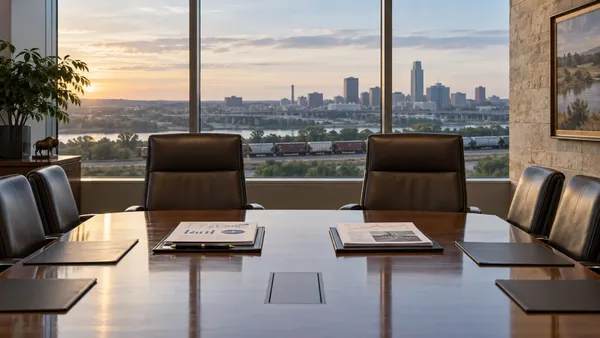 An empty Omaha boardroom with two executive chairs, financial documents and a freight train visible beyond the windows.