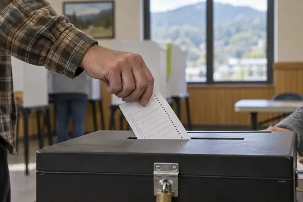 Anonymous voter placing a generic paper ballot into a secure ballot box