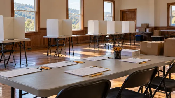 Empty community polling place prepared with privacy booths, blank sign-in sheets, pencils and sealed supply boxes