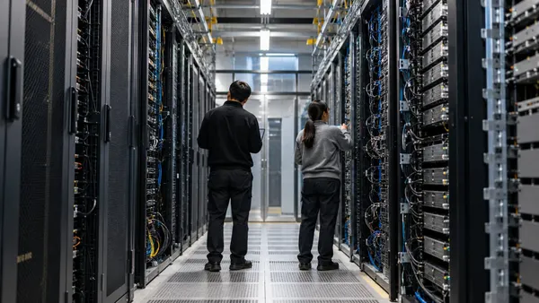 Iniinspeksyon ng dalawang data-center engineer ang mga walang brand na server rack sa isang high-density computing facility.
