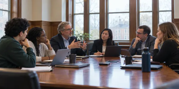 Os administradores universitários, os membros do corpo docente e os estudantes discutem a governação do campus numa sala de conferências genérica.