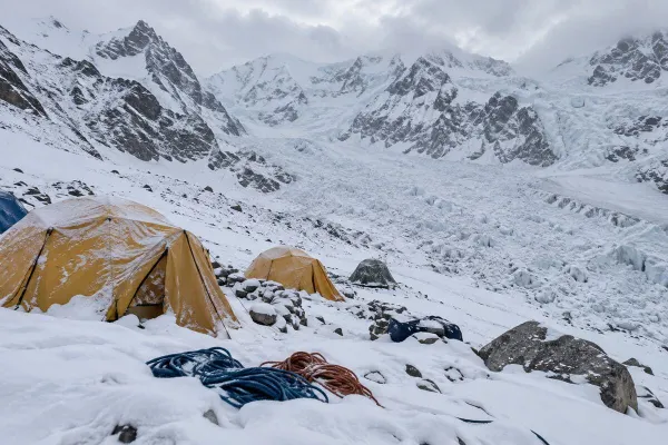 Ilustratibong larawang editoryal ng isang walang laman na kampo ng ekspedisyon sa Himalayas na natatakpan ng niyebe sa ilalim ng matarik na dalisdis ng bundok