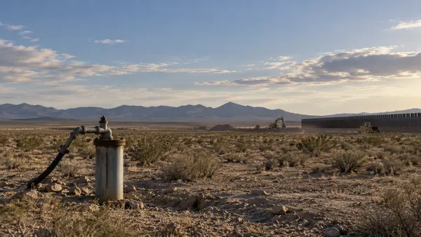 AI-generated editorial image of an unbranded groundwater well pipe in a broad southern New Mexico desert construction landscape.