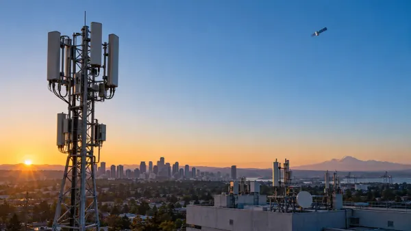Cellular antennas and a communications satellite above a city at dawn, illustrating a hybrid wireless network