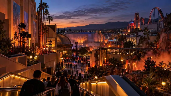 Guests descending into a Southern California movie-studio theme park illuminated for an autumn nighttime event