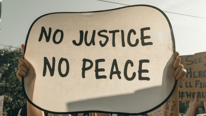 Protester holds a sign saying "No Justice, No Peace"