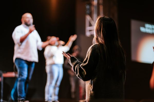 A woman raises her hands in worship during a church service