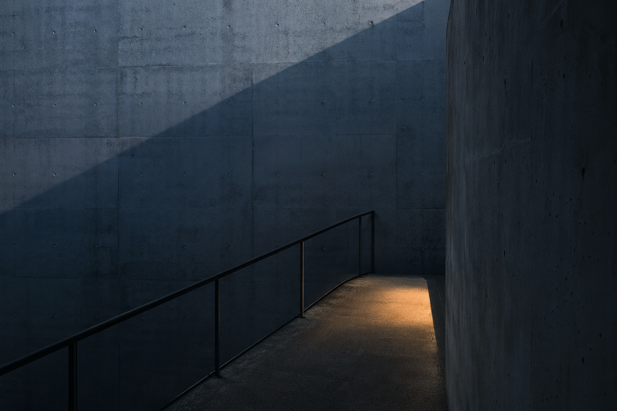 empty blue-grey stairwell with a clean metal railing and one warm pool of light