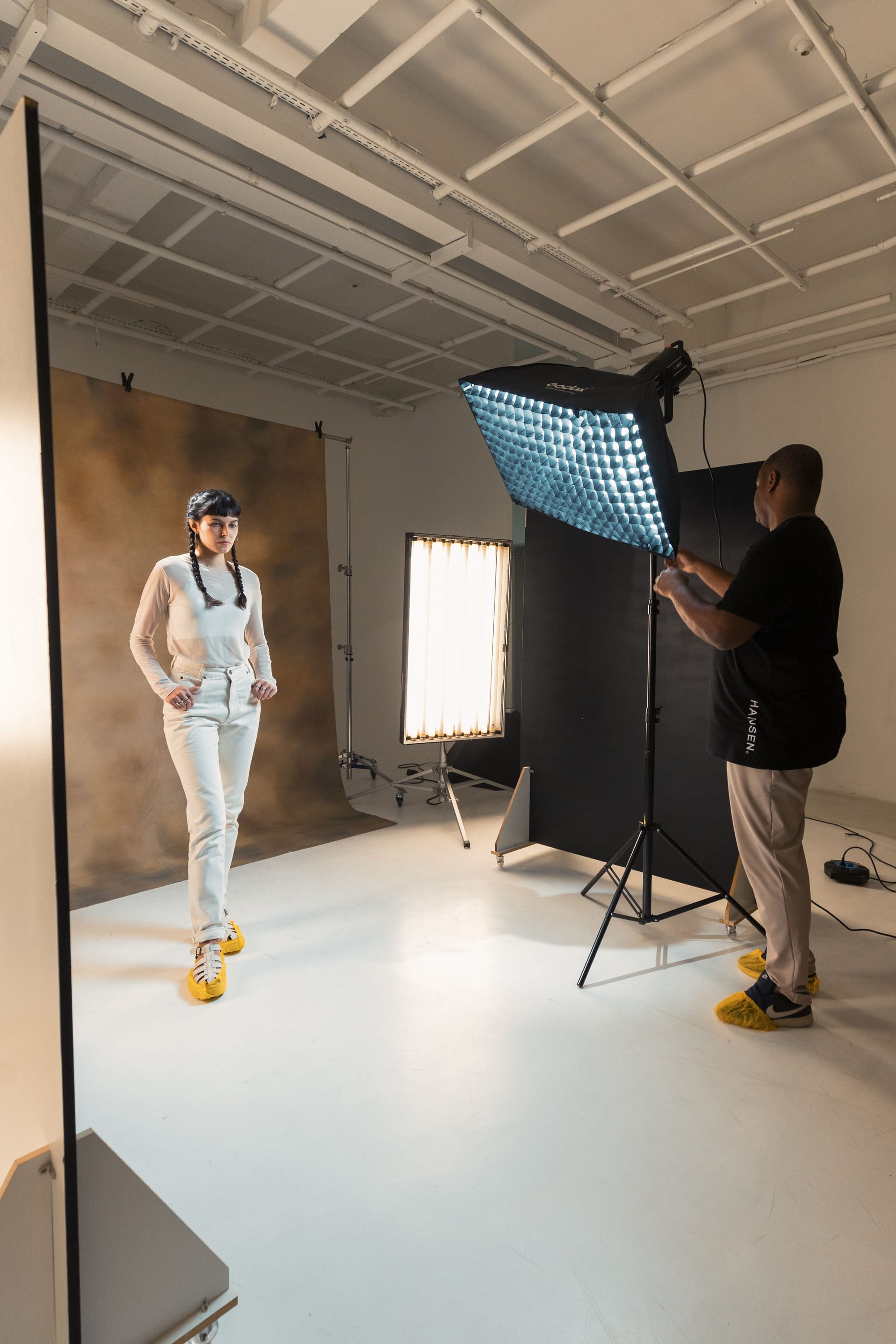 Studio product shoot costs: a model posing under studio lights while a photographer shoots against a white backdrop