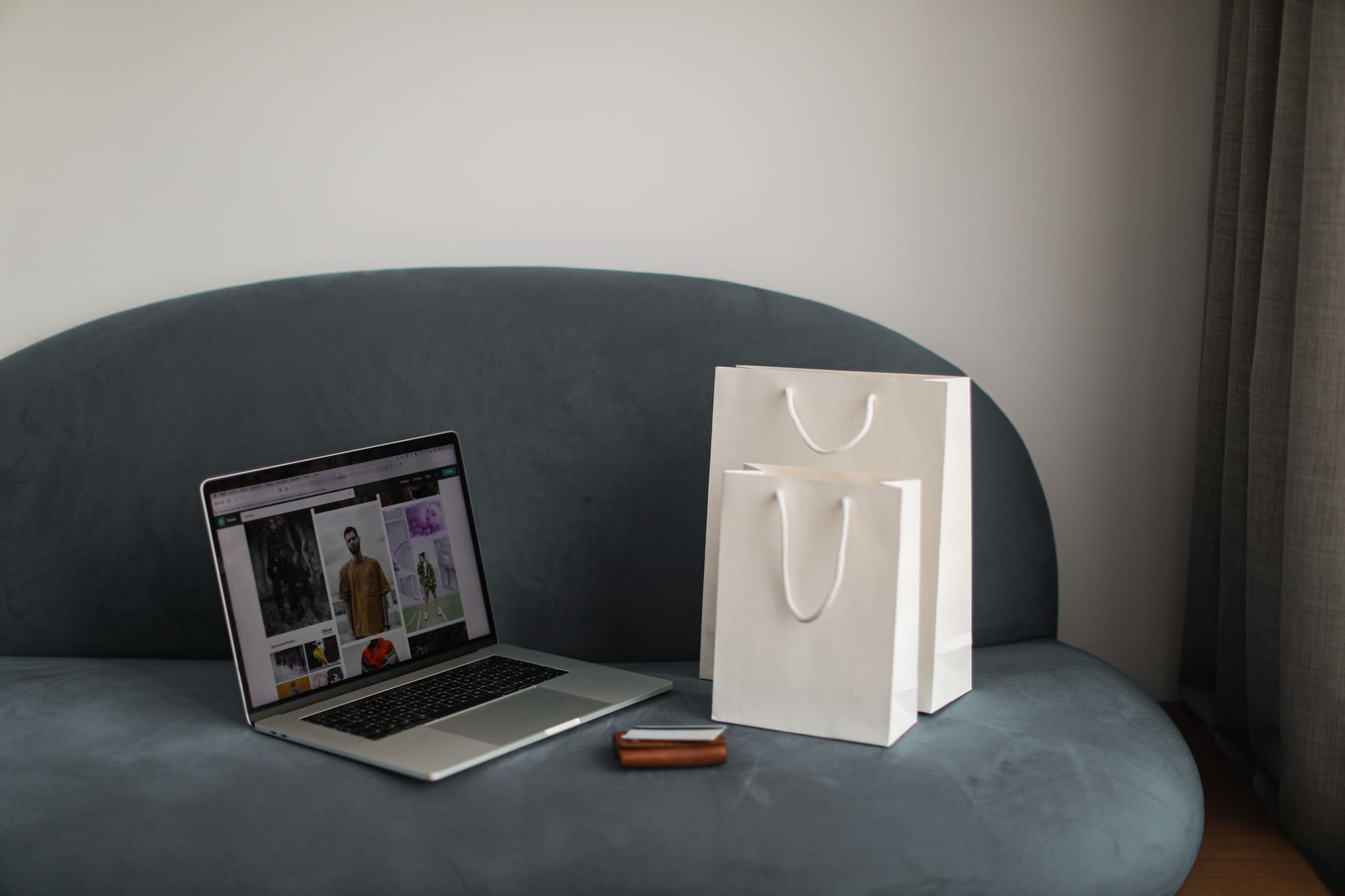 Superfan wallet pass channel for repeat customers: laptop showing an online clothing store beside a paper shopping bag
