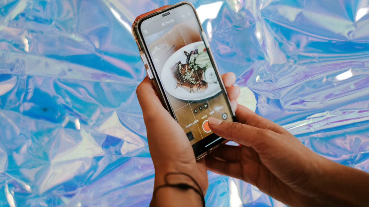 Restaurant loyalty platform with Apple and Google Wallet integration: a diner photographing a plated dish on a phone
