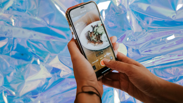 Restaurant loyalty platform with Apple and Google Wallet integration: a diner photographing a plated dish on a phone